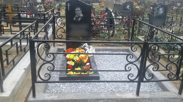 Кованая ограда с завитками и белой отсыпкой у памятника