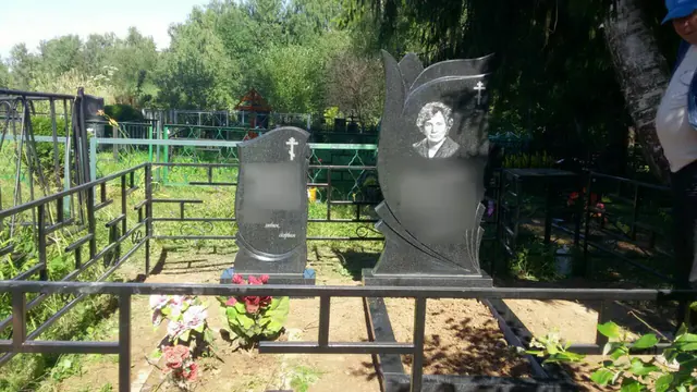 Две стелы разной формы на общем основании за металлической оградой