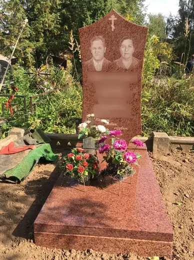 Памятник красного оттенка с двумя портретами и закрытой плитой