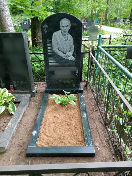 Овальный черный памятник с поясным портретом и цветником