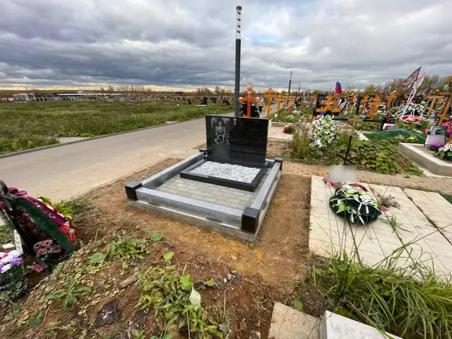 Горизонтальный черный памятник у дорожки на открытом участке