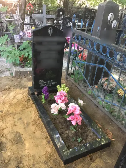 Арочный памятник с небольшим портретом и цветущим цветником