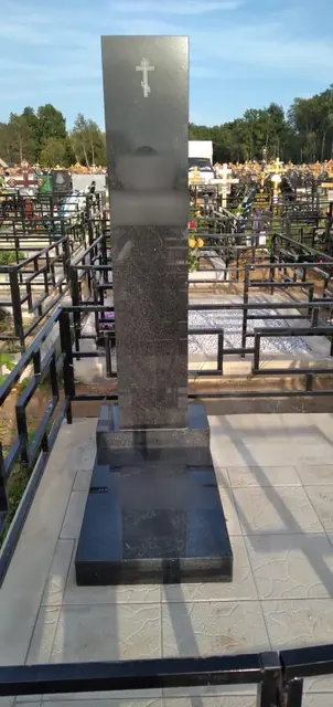 Высокая прямоугольная стела с крестом на площадке со светлой плиткой