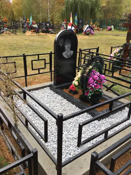 Арочный портретный памятник на белой крошке за строгой оградой