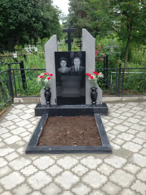 Памятник с центральным крестом, светлыми боковыми частями и цветником
