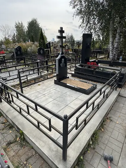 Высокий черный крест на просторном участке со светлой плиткой