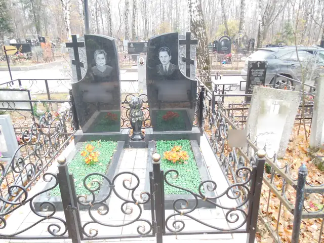 Парные памятники с резными крестами и зелёными цветниками