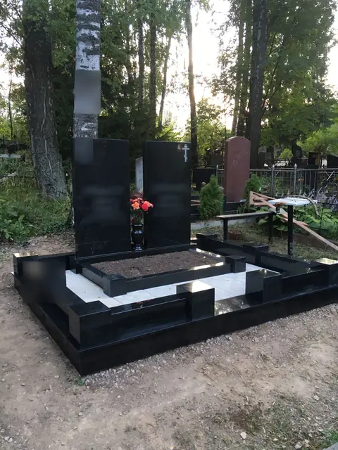 Две строгие черные стелы с общим цоколем среди берез