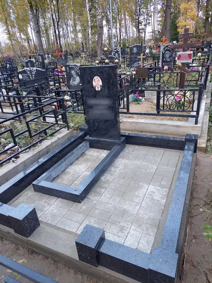Темный гранитный цоколь с двухцветным мощением и черной стелой