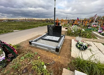 Горизонтальный черный памятник у дорожки на открытом участке