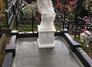 Белая скульптура ангела на участке с гранитным цоколем