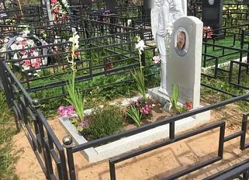Светлый памятник с резным ангелом внутри строгой ограды