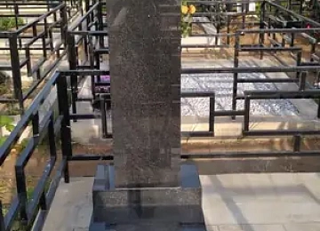 Высокая прямоугольная стела с крестом на площадке со светлой плиткой