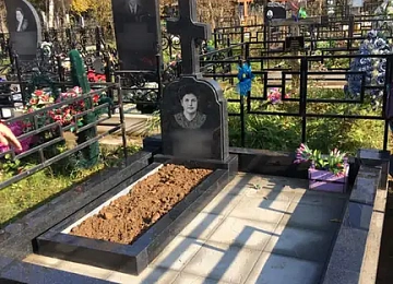 Высокий чёрный крест на гранитном основании с цветником