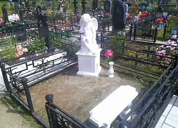 Белая скульптура ангела на постаменте в кованой ограде