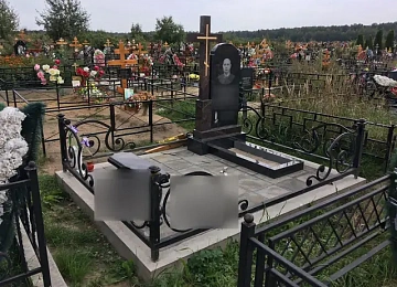 Кованая ограда с крупными завитками вокруг одиночного памятника